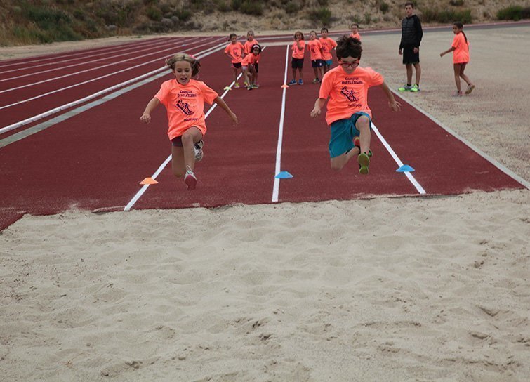 Els nens i nenes practiquen el salt de llargada a la pista d'atletisme
