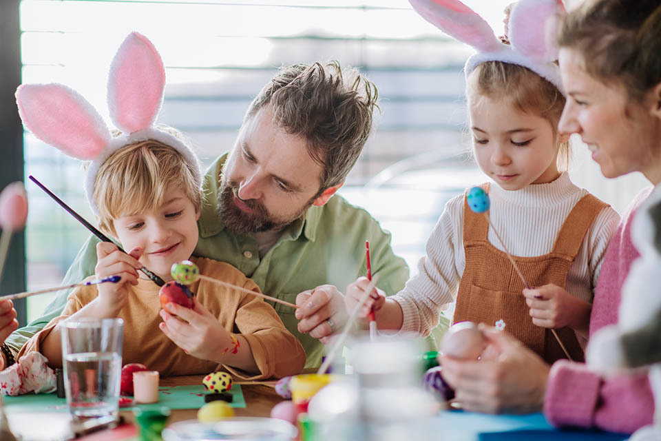 Happy family with little kids decorating easter eggs in their home.