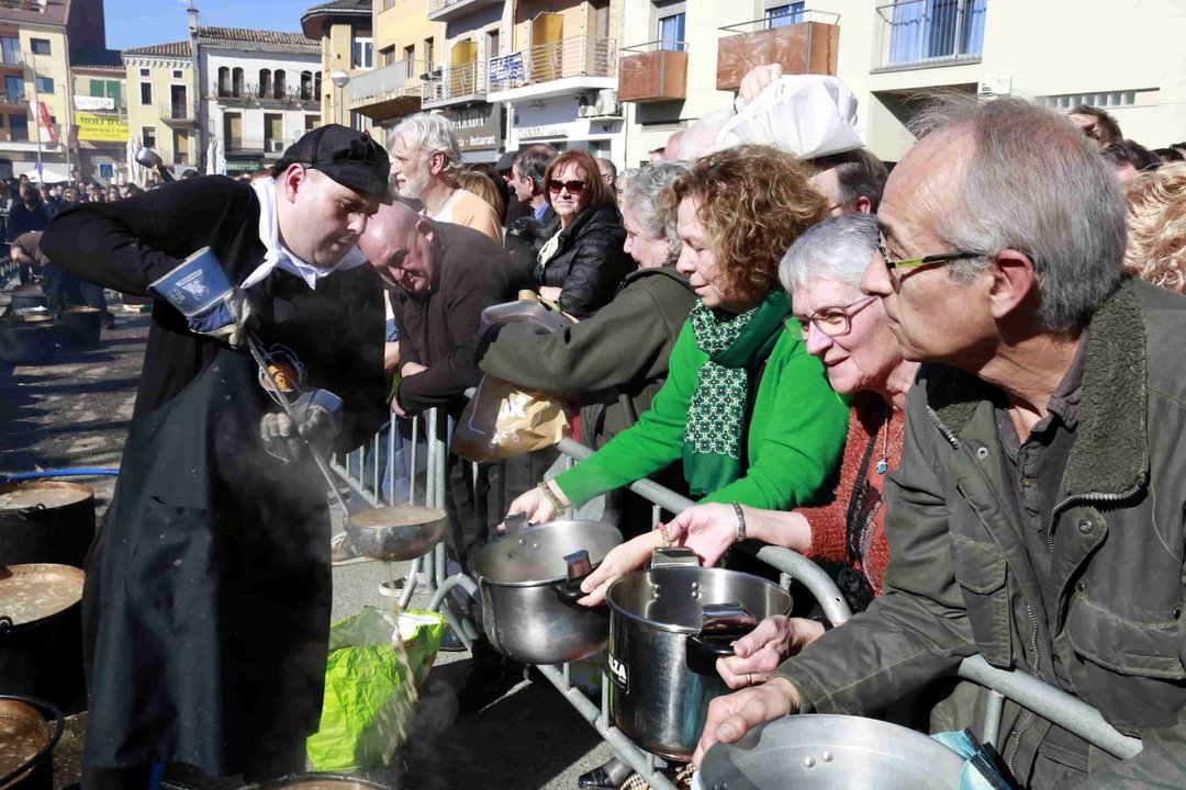 Un membre de l'organització del Ranxo de Ponts repartint el plat a les olles que la gent ha portat de casa - Foto: Anna Berga