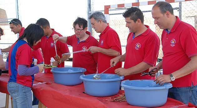 Els membres de la Penya Blaugrna preparen la botifarra i la llonganissa.