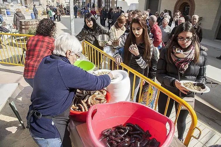 Els veïns i visitants recullen els embotits de la matança a Montgai