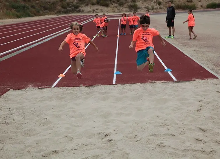 Els nens i nenes practiquen el salt de llargada a la pista d'atletisme