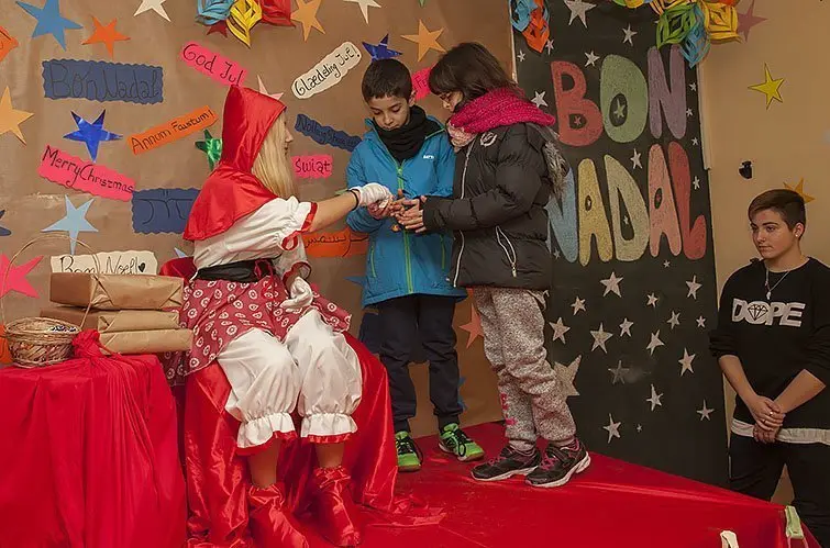 La vermelleta de Creu Roja lliura els regals als infants Interior