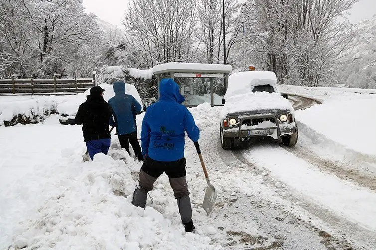 Diverses persones amb una pala al costat de la carretera a Altron