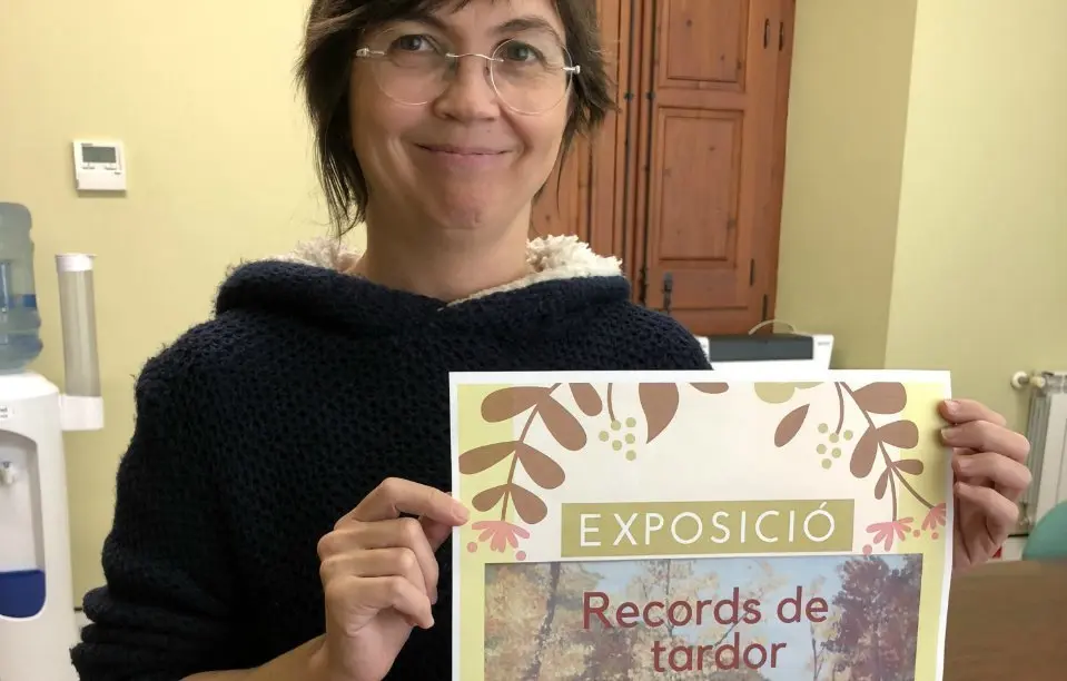 La neboda de l'artista Montse Esteller amb el cartell de l'exposició