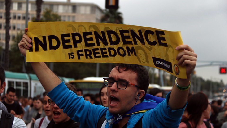 Primer pla d'un estudiant amb el cartell 'INdependence is Freedom', a la Diagonal de Barcelona.