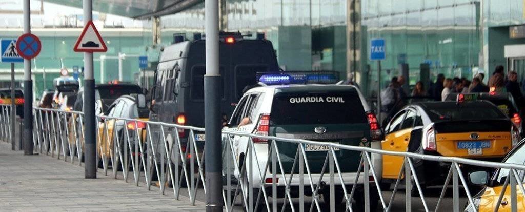 Pla mitjà des de darrere d'una furgoneta i un totterreny de la Guàrdia Civil davant la zona de sortides de la T-1 de l'aeroport del Prat, el 12-10-19 (horitzontal).