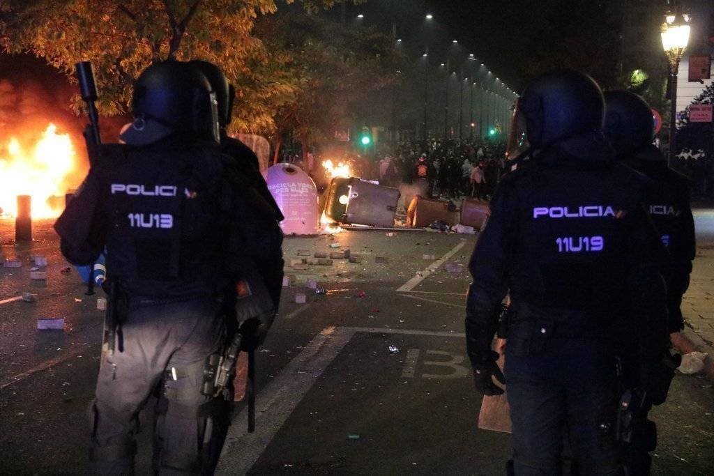 Antiavalots de la policia espanyola observant contenidors encesos i els manifestants, al fons, a l'avinguda de Blondel de Lleida, el 16 d'octubre del 2019. (Horitzontal)