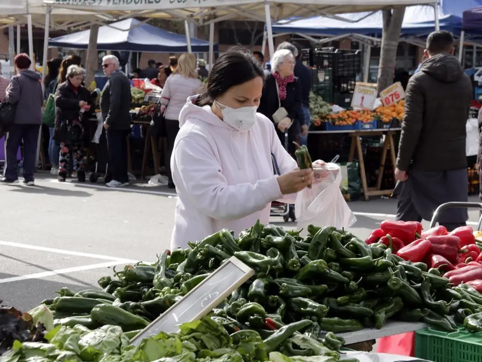 Pla mitjà d'una compradora amb mascareta al mercat dels dissabtes de Lleida, el 14 de març de 2020. (Horitzontal)