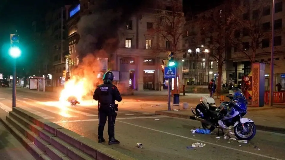 Pla obert d'un Mosso d'Esquadra, dret, a l'avinguda Blondel de Lleida, entre dues motos de la Guàrdia Urbana a terra; una cremada i l'altra amb danys. Imatge del 16 de febrer de 2021. (Horitzontal) - Laura Cortés