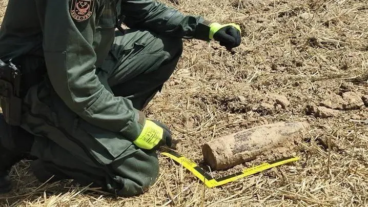 Pla mitjà on es pot veure un agent de la Guàrdia Civil del GEDEX amb la bomba de la Guerra Civil trobada a Artesa de Segre, el 13 d'agost de 2021. (Vertical)