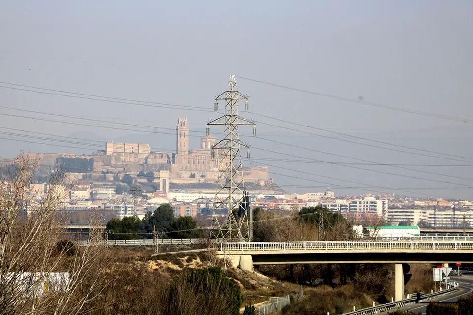 Pla obert on es poden veure diferents torres i línies d'alta tensió amb la Seu Vella de Lleida al fons, des d'Albatàrrec, l'11 de gener de 2022. (Horitzontal)