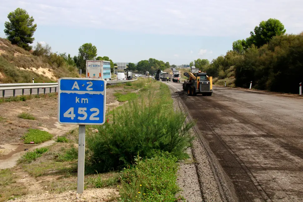 Un cartell del punt quilomètric 452 de l'A-2 i màquines al fons treballant en la millora del ferm de la via - Foto: Anna Berga