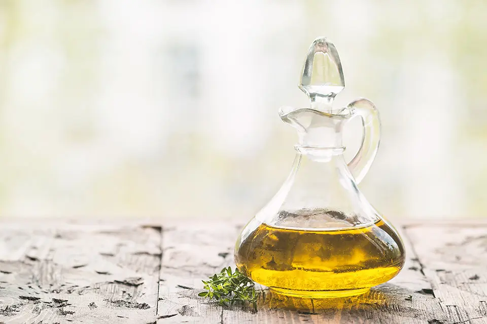 olive oil in glass bottle and olives over old wooden table