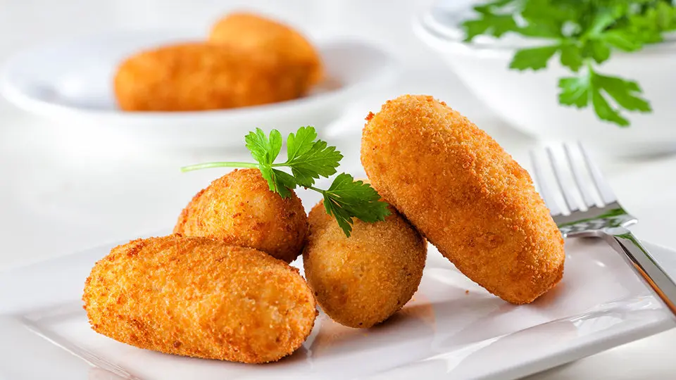 Homemade gourmet croquettes on a white plate with fork- AMIC