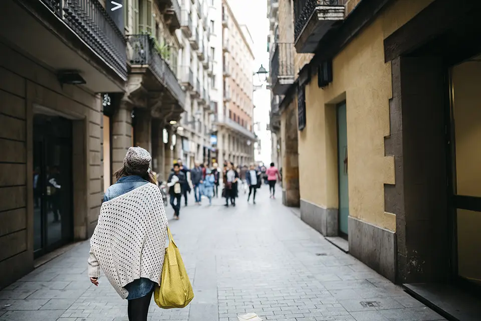 Spain, Barcelona, young woman walking in an alley