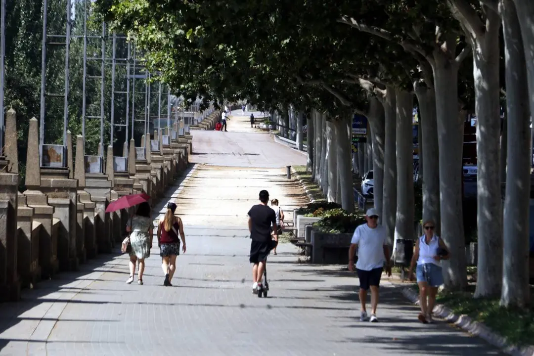 Vianants caminant per l'ombra a Lleida sota una intensa calor