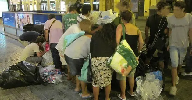 Persones recuperant aliments en un contenidor d'una gran superfície.