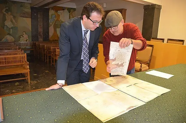 L'alcalde Marc Solsona i l'arxiver Josep Maria Cabau observen els docoments.
