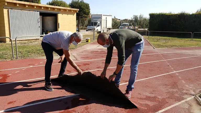 L'alcalde d'Arbeca, Sergi Pelegrí, i el tinent d'alcalde Francesc Roset, aixecant una part del terra de la pista d'atletisme
