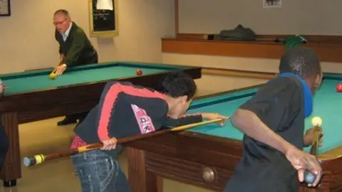 Els avis ensenyen als joves a jugar al billar en el Casal Municipal.