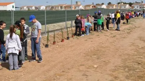 Els alumnes i docents en plena feina al voltant del camp de futbol.