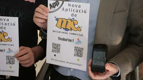 El cartell des de on es pot descarregar l'aplicació i aquesta en un mòbil.