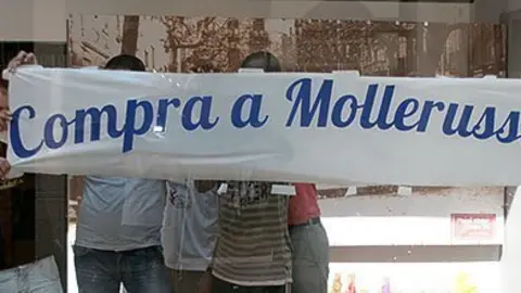 Els joves contractats al SOC preparen l&#39;aparador del local buit de jacint Berdaguer.