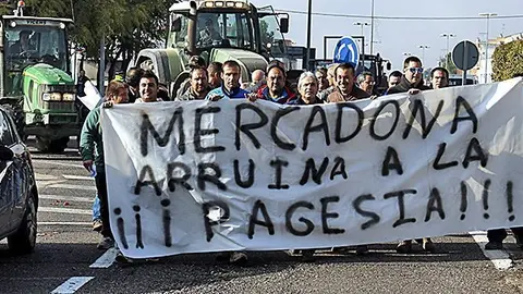 Pla general dels pagesos amb una pancarta acusant a Mercadona dirigint-se al nou supermercat que la cadena ha obert a Mollerussa, el 28 de novembre de 2016 (Horitzontal)