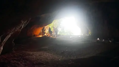 La Cova del Tabac des de l'interior, amb arqueòlegs del CEPAP UAB treballant a l'entrada. Imatge del 3 d'agost de 2018. (Horitzontal)