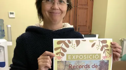 La neboda de l'artista Montse Esteller amb el cartell de l'exposició