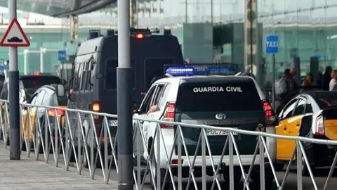 Pla mitjà des de darrere d'una furgoneta i un totterreny de la Guàrdia Civil davant la zona de sortides de la T-1 de l'aeroport del Prat, el 12-10-19 (horitzontal).