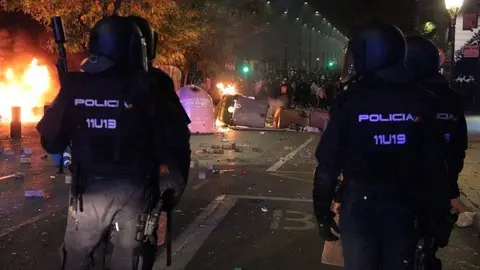 Antiavalots de la policia espanyola observant contenidors encesos i els manifestants, al fons, a l'avinguda de Blondel de Lleida, el 16 d'octubre del 2019. (Horitzontal)