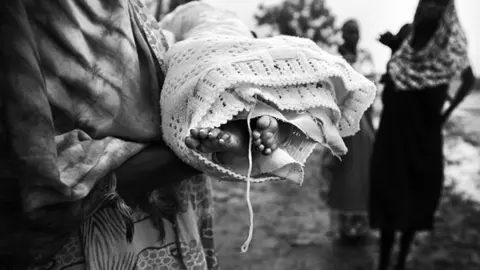 A relative holds the dead body of (right) Nyamuoch Kuoch's baby