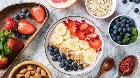 Smoothie bowl with banana slices, strawberry, blueberries, granola and pomegranate seeds. Top view. Healthy lifestyle, healthy eating, dieting, weight loss concept