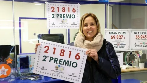 La responsable de l'administració número 14 de Pi i Margall, de Lleida, amb un cartell que indica que ha venut una sèrie del segon premi, el número 21.816. Imatge del 6 de gener del 2019. (horitzontal)