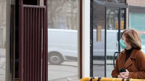 Una vianant amb mascareta observa botigues tancades