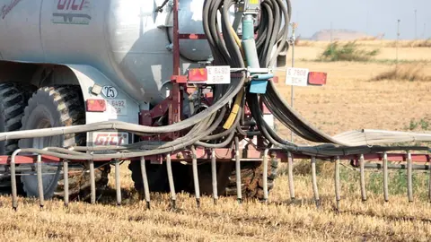 Pla detall d'un tractor amb una cisterna aplicant purins en una finca d'Albesa mitjançant el sistema de tubs penjants, el 3 de juliol del 2019. (Horitzontal)