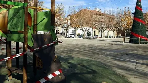 Pla general on es pot veure la plaça del Planell de Linyola, amb una instal·lació infantil precintada i un gran arbre de Nadal, el 16 de desembre de 2020. (Horitzontal)