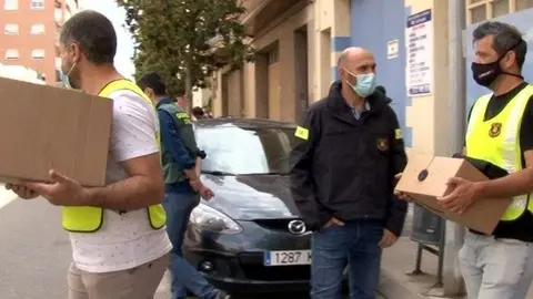 Mossos d'Esquadra sortint amb caixes d'un registre fet en un pàrquing de Balaguer.
