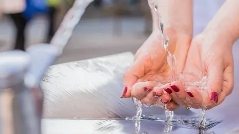 Jove mullant-se en una font.