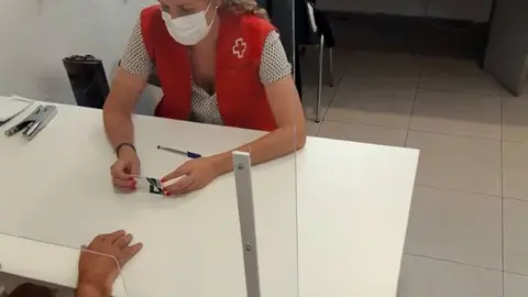 Cedida per la Creu Roja Lleida
Pla mitjà on es pot veure una voluntària de la Creu Roja Lleida repartint targetes aliment. (Vertical)