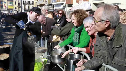 Un membre de l'organització del Ranxo de Ponts repartint el plat a les olles que la gent ha portat de casa - Foto: Anna Berga
