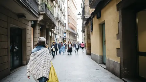 Spain, Barcelona, young woman walking in an alley