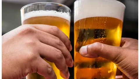 Imatge de dues persones brindan amb cervesa. Foto Pexels