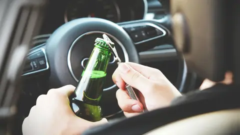 Imatge d'una persona obrint una ampolla de cervessa al cotxe. Foto: Pexels