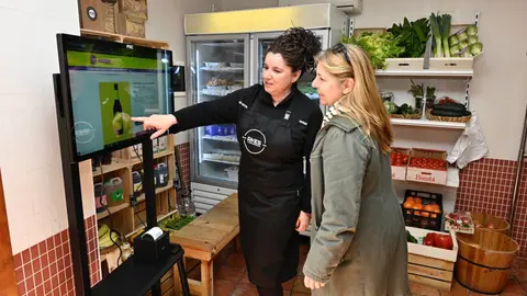La responsable d'una botiga mostra a una clienta la pantalla tàctil de la iniciativa 'Al poble hi ha de tot' a Sarroca de Lleida. Foto:  ACN