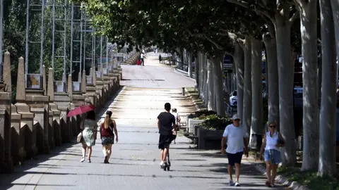 Vianants caminant per l'ombra a Lleida sota una intensa calor