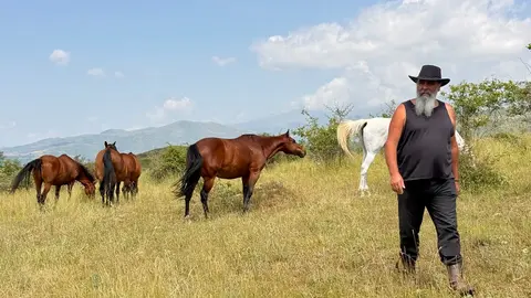 Pere Cases, el responsable de Cavalls Wakan que es dedica al retir de cavalls a Montcortès, al Pallars Sobirà, amb els cavalls al fons. Foto ACN
