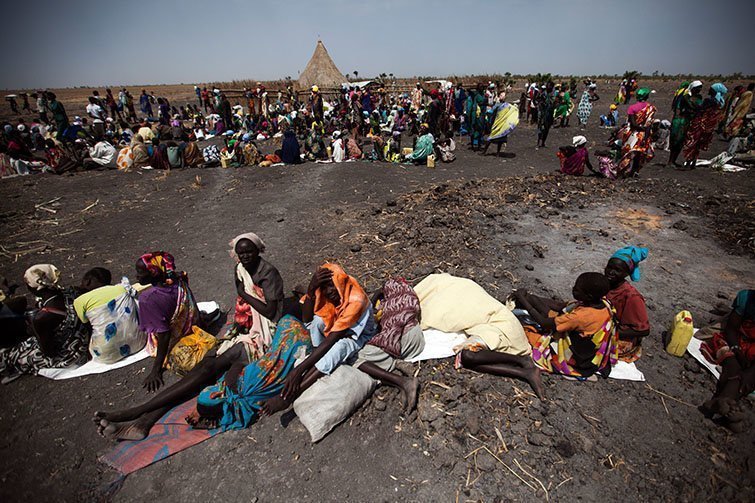 3 February 2016. Thonyor: A large number of people wait  for food air-drops by ICRC, outside Thonyor, in South Sudan. ICRC is conducting an operation of food distribution for around 25,000 civilians who are still suffering food crisis since the armed clashes broke out in October 2015.Fighting between Army forces and Sudan People's Liberation Movement in Opposition (SPLM-IO) took place following a brief takeover the neighbour town of Leer by rebel forces on October 2, 2015. Government forces pushed the rebels out later that day. The clashes were followed with intensive looting by armed men who entered the all humanitarian compounds and stole equipment, medical supplies and money. The humanitarian personnel were evacuated and didn't regained access until December, but it's not fully operational yet. Thonyor is still under control of the opposition movement.Photo by Albert Gonzalez Farran - AFP